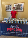Table of logo labeled Signature Popcorn giveaway bags at a Visit Tampa Bay event